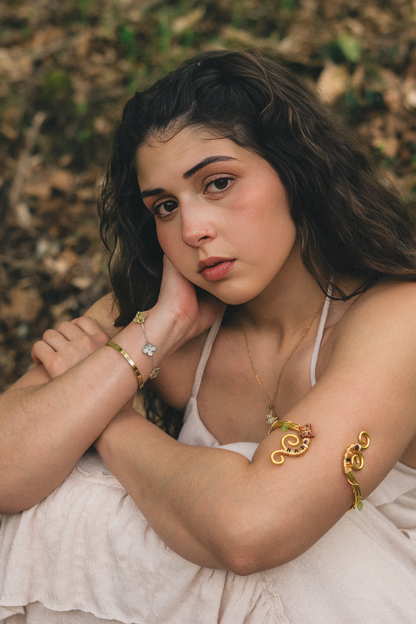 Retrato de mujer con aretes dorados y las manos cruzadas al pecho