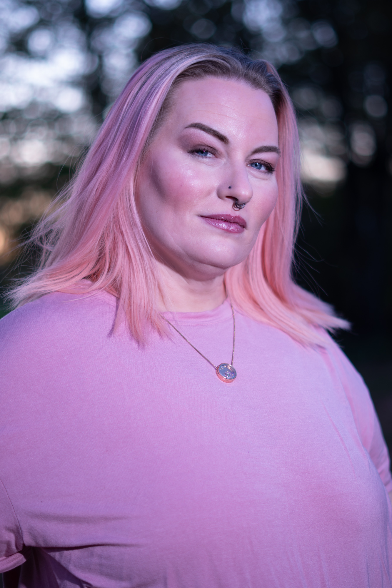 Retrato cercano de mujer de cabello rosa con camiseta lila