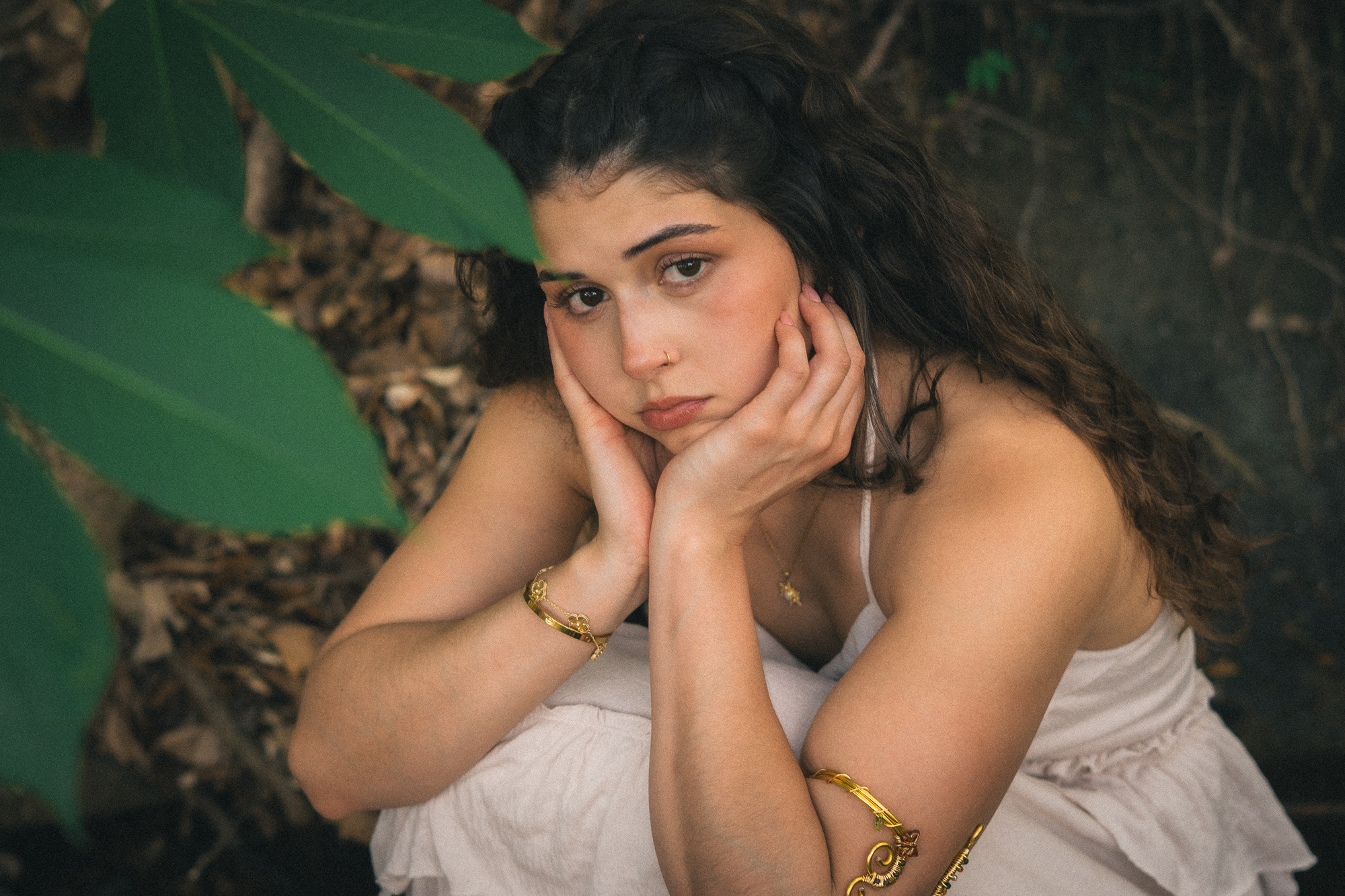 Retrato de mujer con la mano en el rostro entre la vegetación