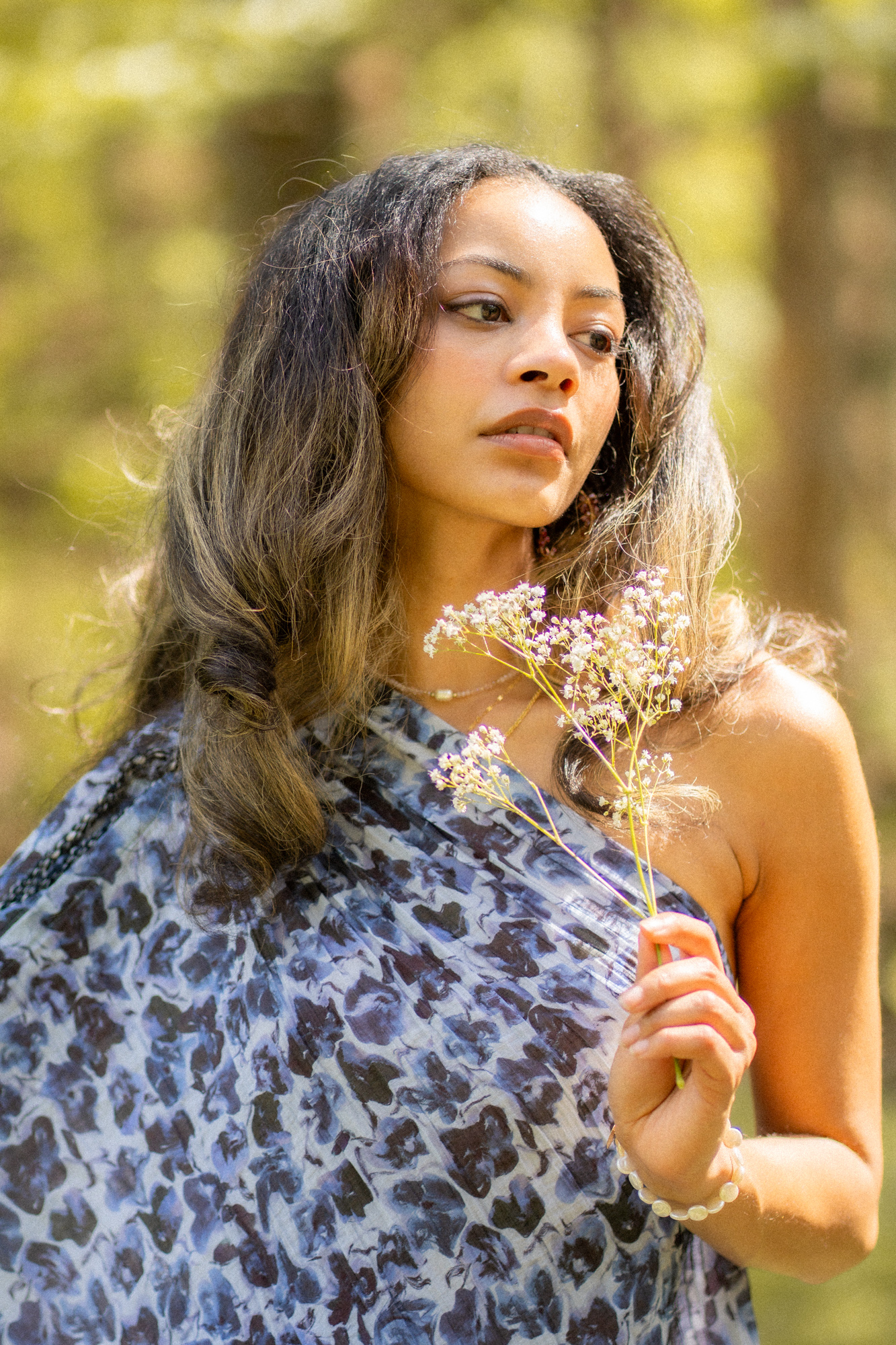 Retrato a contraluz de mujer con vestido floreado y ramas secas